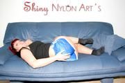 Red-haired Jill Diamond wearing a blue shiny nylon shorts and a black top posing on a blue sofa (Pics)