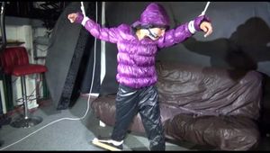 Sexy Sandra being tied and gagged overhead with ropes and a bar wearing a sexy black rain pants and a purple down jacket with hood closed (Video)