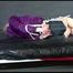 Pia tied and gagged with belts on a bed wearing a sexy black shiny nylon shorts and a purple rain jacket (Video)