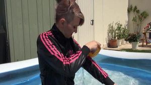 Mara wearing a shiny black/pink adidas training suit playing with water in the pool (Video)