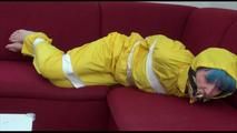 Mara tied and gagged with tape on a sofa wearing a sexy shiny yellow rainwear combination (Video)