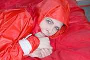 Destiny wearing a sexy red rain suit tied and gagged and hooded with ropes and a cloth gag on a bed (Pics)