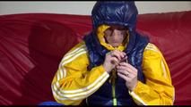 Sonja ties, gagges and hoodes herself on a sofa with a bar and a ball gag wearing a sexy blue shiny nylon rain pants and a yellow rain acket and a blue down jacket (Video)