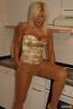 Natural busty Martina posing in a golden corsage, black leggins, pantyhose and heels in the kitchen