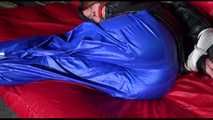 Sonja wearing a sexy blue raver shiny nylon pants and a black down jacket being tied, gagged and hooded on a sofa with ropes (Video)