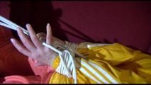 Lucy tied, gagged and hooded on a red sofa wearing a sexy orange shiny nylon pants and a yellow rain jacket (Video)