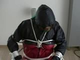 Katharina tied, gagged and hooded on a chair wearing shiny nylon rainwear and over it an rain cape (Video)