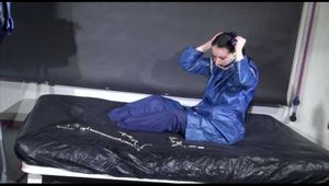 Lucy ties and gagges herself with cuffs on a bed wearing sexy blue shiny nylon rainwear (Video)