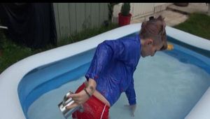 Mara in the swimming pool wearing a sexy red shiny nylon shorts and a lightblue sihny rain jacket playing with the water (Video)