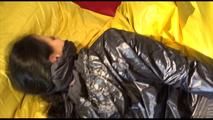 Lucy tied and gagged on bed wearing a sexy black shiny nylon pants and a black rain jacket (Video)