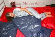 Alina lolling and posing in bed wearing a sexy grey adidas shiny nylon rainwear jumpsuit (Pics)