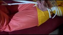 Lucy tied, gagged and hooded on a red sofa wearing a sexy orange shiny nylon pants and a yellow rain jacket (Video)