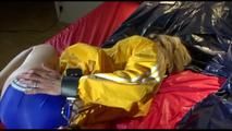 Sonja tied and gagged with a bar and cuffs in bed wearing a very small, hot blue shiny nylon shorts and a yellow rain jacket (Video)