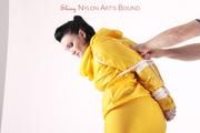 Jill tied and gagged in a shiny yellow rainsuit and rubber boots