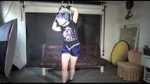 Mara wearing a sexy darkblue/purple shiny nylon shorts tied and gagged overhead with ropes and ballgag as well as a bar on the feet (Video)