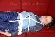 Lucy wearing a blue shiny nylon pants and an oldschool blue rain jacket tied and gagged with ropes on a sofa (Pics)