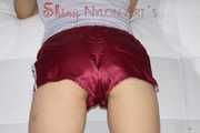 Sexy Sandra wearing a very shiny bordeaux red shiny nylon shorts and a grey top posing for you on a sofa (Pics)