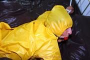 Stella tied and gagged in a shiny yellow rainsuit