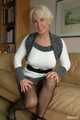 Pierced MILF Claudia posing in a knitted dress and pantyhose on the couch