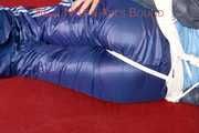 Lucy wearing a blue shiny nylon pants and an oldschool blue rain jacket tied and gagged with ropes on a sofa (Pics)