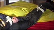 Lucy tied and gagged on bed wearing a sexy black shiny nylon pants and a black rain jacket (Video)