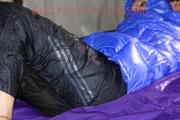 Pia tied, gagged and hooded with cuffs and chains on a bed wearing a sexy black rain pants and a blue down jacket (Pics)