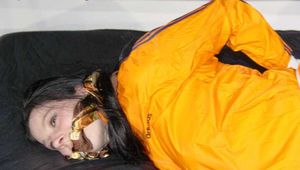Lucy tied and gagged with ropes on a sofa wearing a sexy blue shiny nylon shorts and an orange rain jacket (Pics)