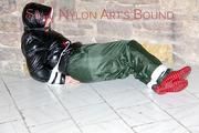 Jill tied, gagged and hooded on a cellar floor wearing a shiny green rain pants and a shiny black down jacket (Pics)