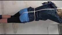 Pia tied and gagged over head in a laundry wearing a supersexy black leggins and a blue shiny nylon adidas shorts as well as a blue rain jacket (Video) 