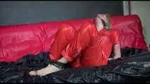 Pia wearing an supersexy red rain catsuit tied and gagged with neck ties on a sofa (Video)