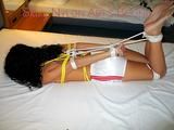 An archive girl tied, gagged and blind folded on a bed wearing only a white shiny nylon shorts (Pics)