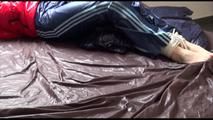 Mara tied and gagged on bed wearing a sexy shiny red down jacket and a blue rain pants (Video)