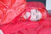 Destiny wearing a sexy red rain suit tied and gagged and hooded with ropes and a cloth gag on a bed (Pics)