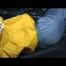 Samantha in a shiny yellow rain jacket and a shiny grey rain trowsers tied and gagged on bed (Video)