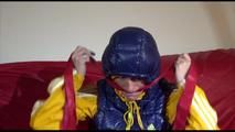 Sonja ties, gagges and hoodes herself on a sofa with a bar and a ball gag wearing a sexy blue shiny nylon rain pants and a yellow rain acket and a blue down jacket (Video)