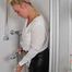 Blonde Frida takes a shower in her white shirt and black glossy pants